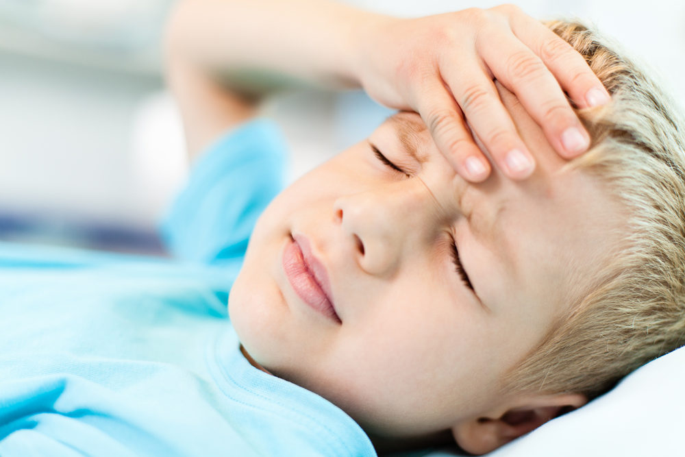 Boy lying down holding his forehead