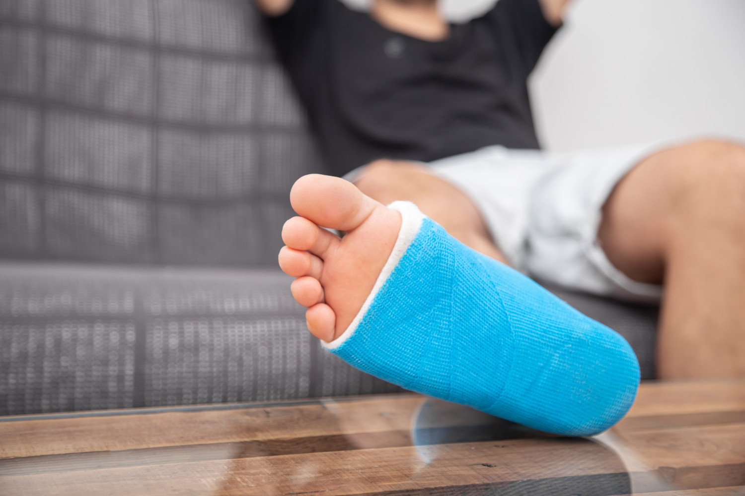 Person resting on a couch with a blue cast on their lower leg