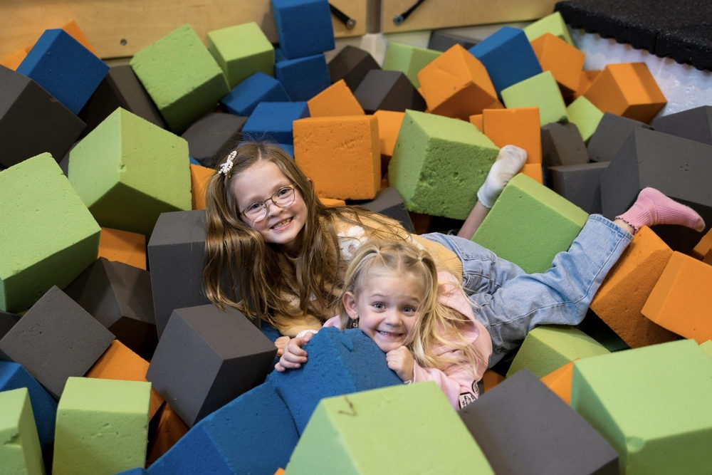Two smiling girls in a foam block pit