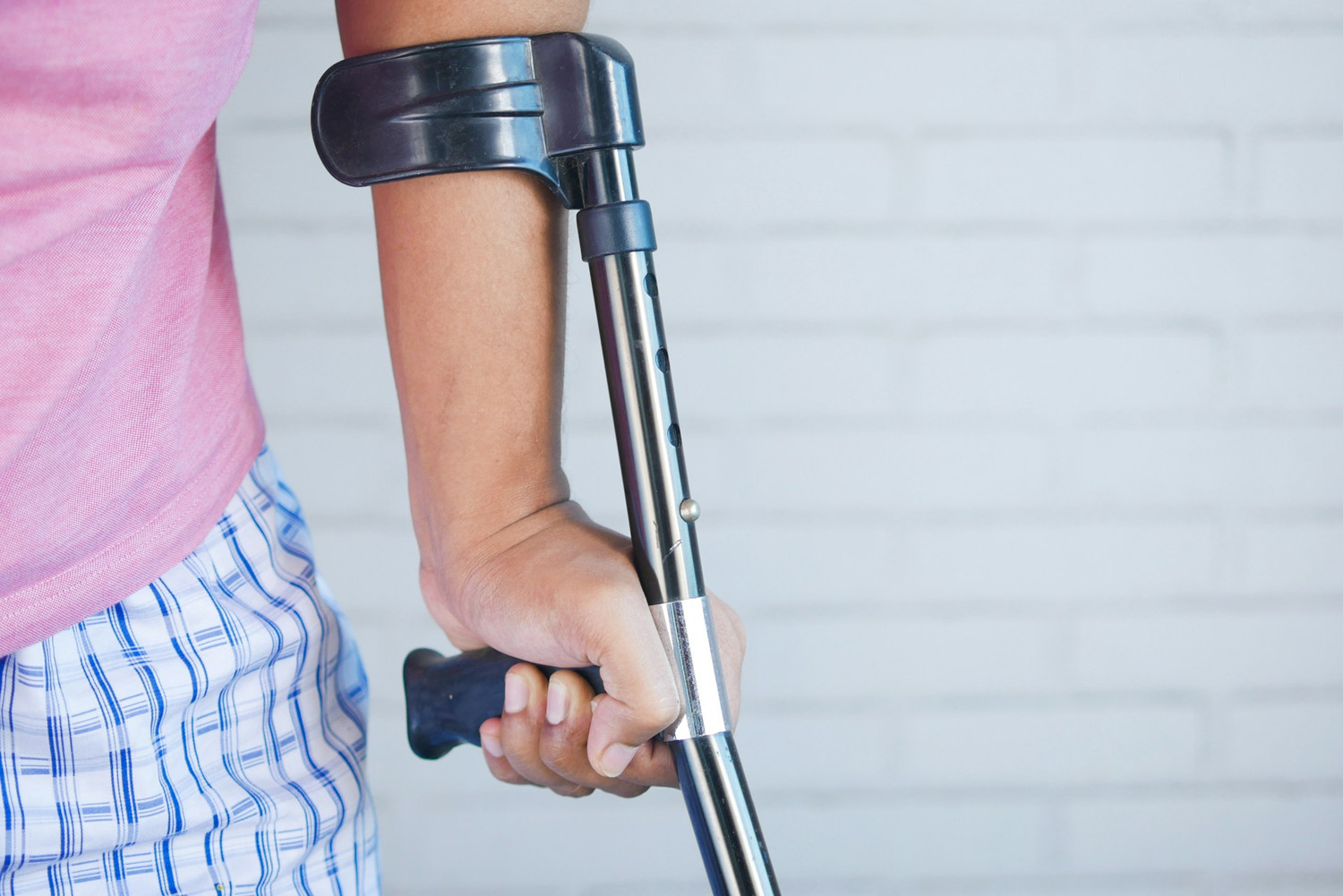 Hand gripping the handle of a forearm crutch