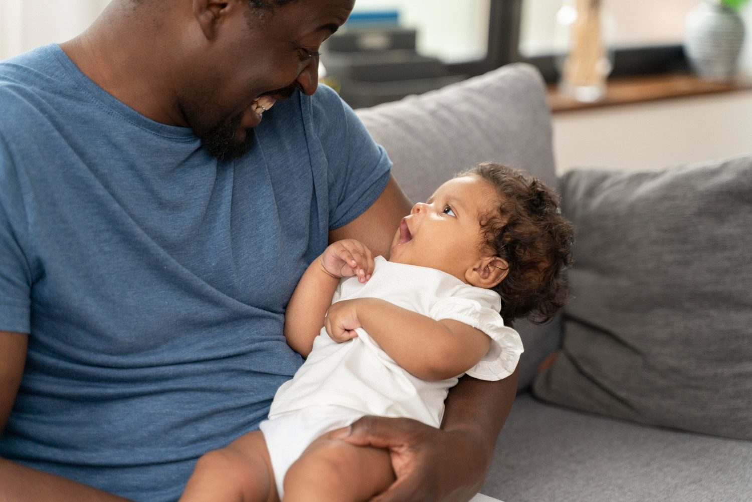 Smiling father holding a baby who looks up at him from his lap