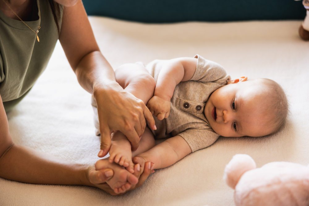 Adult positioning a smiling infant lying on its side